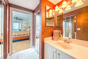 Une salle de bain moderne avec un grand miroir, un lavabo blanc et un ventilateur de plafond.