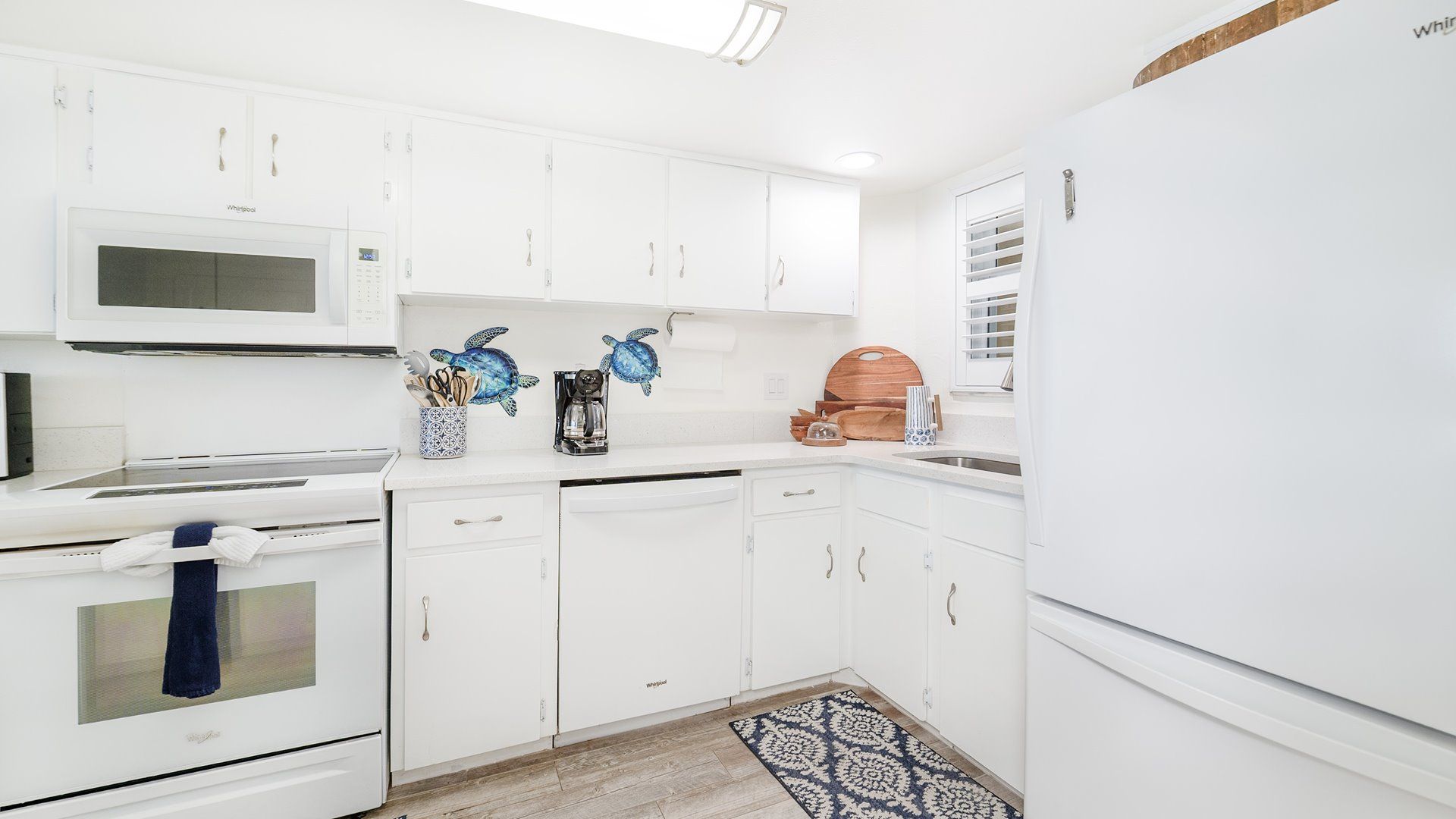 A modern kitchen with white cabinetry, a microwave, a stove, a dishwasher, and a refrigerator.