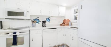 A modern kitchen with white cabinetry, a microwave, a stove, a dishwasher, and a refrigerator.