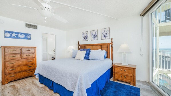 Un dormitorio con cama, cómoda de madera, ventilador de techo, obra de arte y vista al océano.