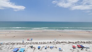 A beach with clear skies, calm sea, and several beach umbrellas.