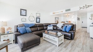 A modern living room with a sectional sofa, a coffee table, and a dining area.