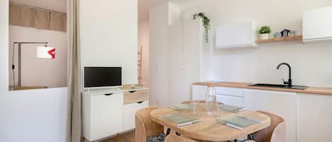 Eine moderne Küche mit weißen Schränken, einem Holztisch und einem integrierten Fernseher.
