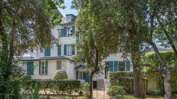 Un immeuble de deux étages avec un jardin à l’avant.