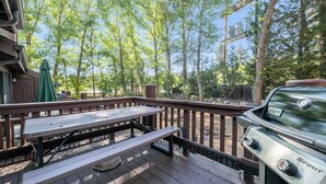 Une terrasse en bois avec des tables de pique-nique et un barbecue.