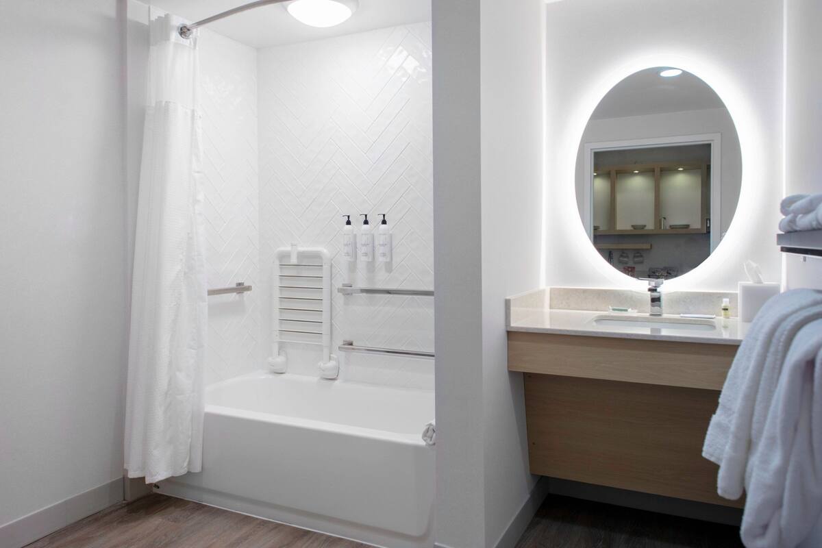 Un baño moderno con ducha, bañera, tocador con espejo y artículos de aseo en la pared.