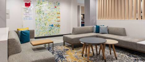 A modern hotel lobby with a sofa set, a coffee table, and a map on the wall.