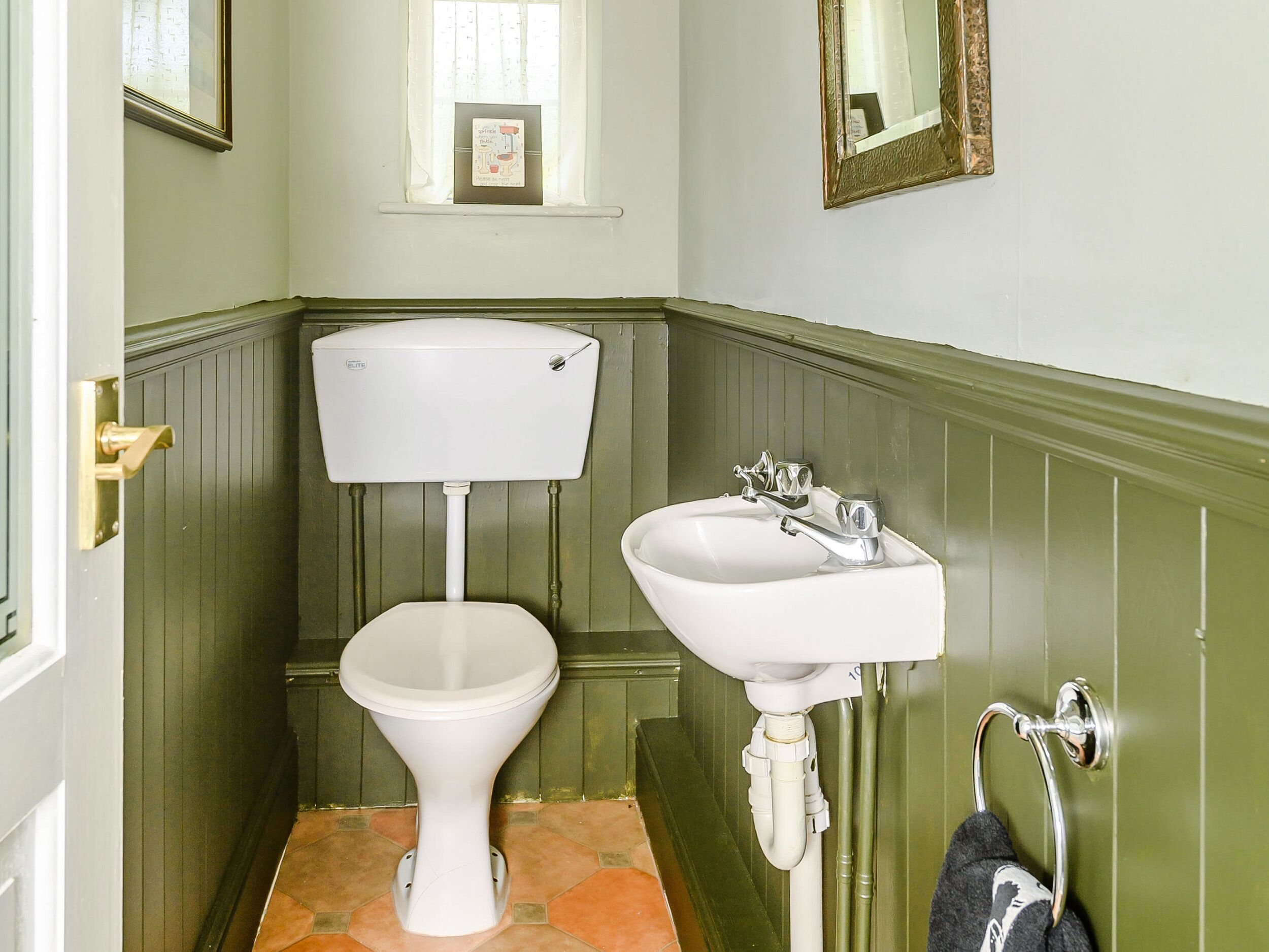 A bathroom with a toilet, sink, and mirror.