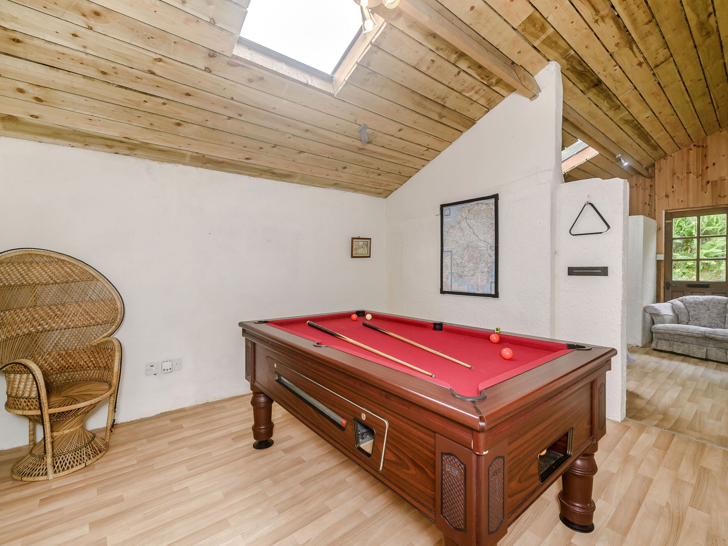 A pool table in a room with wooden floors and a high ceiling.