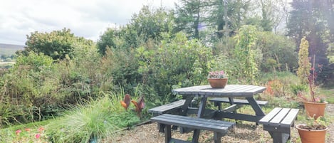 Una mesa de picnic con banco, rodeada de grava y plantas en macetas.