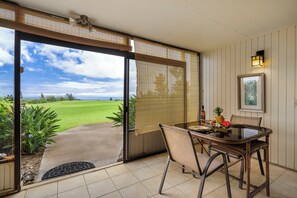 Un comedor con una mesa y sillas, vista a un campo de golf, y una puerta que da a un espacio exterior.