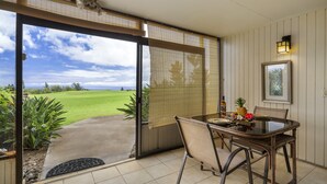 A dining area with a table and chairs, a view of a golf course, and a door leading to an outdoor space.