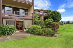 Un edifici residencial de diverses plantes amb un balcó, un jardí ben cuidat i un cel serè.