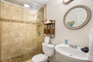 Un baño con ducha, inodoro, lavamanos y espejo.