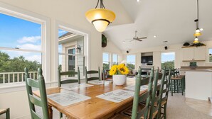 A dining area with a wooden table, green chairs, and a vase of sunflowers. - The Hidden Gem: Hot Tub, Private Pool, Currituck Club Amenities (Corolla)