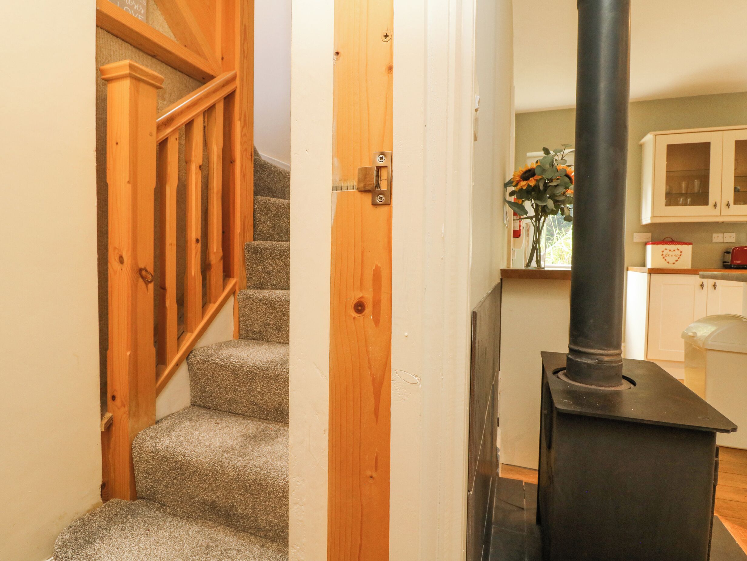 A staircase with wooden railings, a kitchen area with cabinets, and a black stove.