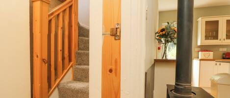 A staircase with wooden railings, a kitchen area with cabinets, and a black stove.
