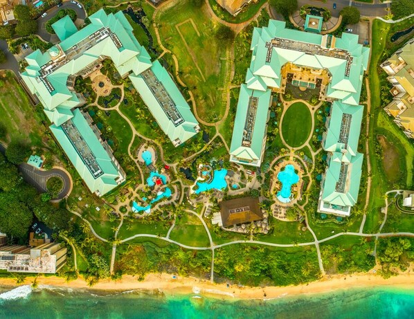An aerial view of a resort with multiple buildings, swimming pools, and a beach.