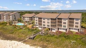 Een appartementencomplex aan het strand, met meerdere gebouwen, een zwembad en een strand op de achtergrond.