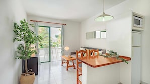 Une cuisine moderne avec un îlot central en bois, des armoires blanches et un four à micro-ondes encastré.