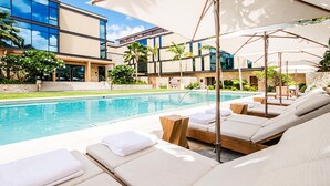 Ein modernes Hotel mit Poolbereich, ausgestattet mit Liegestühlen und Sonnenschirmen.