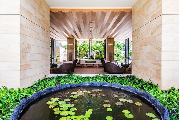 Un jardin intérieur paisible, agrémenté d’un élément aquatique, d’un espace salon et offrant une vue sur l’extérieur.
