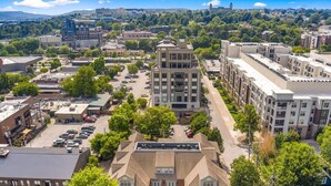 An urban area with a mix of commercial and residential buildings, including a prominent multi-story building with a flat roof and a parking lot in the foreground. - Game Day Getaway - 1 Block to Dickson-Walk to UofA (Fayetteville)