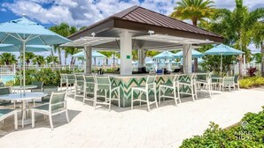 An outdoor seating area with tables and chairs, a covered bar, and umbrellas. - Private Pool Townhome Near Disney Parks (Kissimmee)