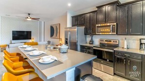 A modern kitchen with dark wood cabinets, stainless steel appliances, and a central island with seating. - Private Pool Townhome Near Disney Parks (Kissimmee)