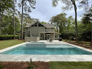A two-story house with a large front yard and a swimming pool.