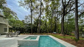 Una piscina rettangolare con gradini d'accesso, circondata da un patio con mobili da esterno.