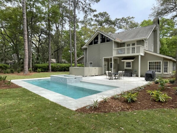 A two-story house with a large backyard, a swimming pool, and a patio area with outdoor furniture.