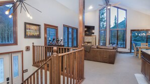 A spacious living area with a wooden staircase, large windows, a fireplace, and a television. - 4515 Bighorn Rd. 4 Bedroom Home by RedAwning (Vail)