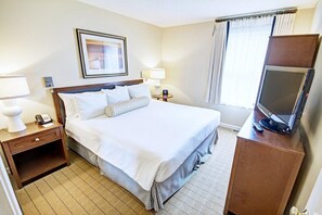 A hotel room with a large bed, bedside tables with lamps, a TV on a wooden cabinet, and a window with curtains.