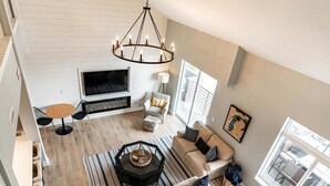 Ein geräumiges Wohnzimmer mit Kamin, großem Fernseher, rundem Couchtisch und einer Couch.
