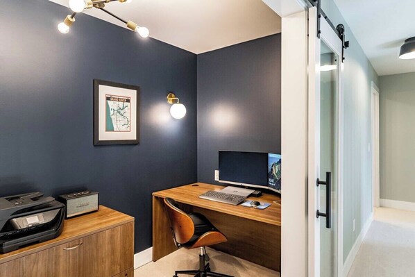 A modern office space with a dark blue wall, a framed map, a desk with a computer, and a printer.