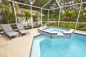 Una piscina con borde alicatado, rodeada por una estructura de metal blanco y dos sillas de descanso.