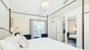 A bedroom with a four-poster bed, a chandelier, a window with curtains, and a door leading to another room. - The Oasis Retreat +Pool +Game Room +Basketball + Massive Yard +Near Beach & Golf (Largo)