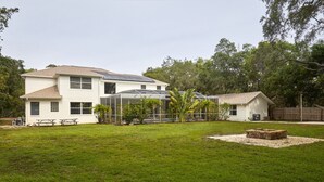 A two-story house with a covered patio area, a fire pit, and a fenced yard. - The Oasis Retreat +Pool +Game Room +Basketball + Massive Yard +Near Beach & Golf (Largo)