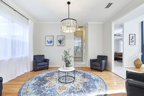 A living room with a round blue rug, two dark armchairs, a white coffee table, and a hanging light fixture. - The Oasis Retreat +Pool +Game Room +Basketball + Massive Yard +Near Beach & Golf (Largo)