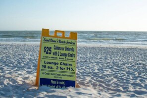 A beachside sign advertising beach services including a $25 option for a cabana or umbrella with lounge chairs, and lounge chairs for $8 each or 2 for $15. - The Oasis Retreat +Pool +Game Room +Basketball + Massive Yard +Near Beach & Golf (Largo)