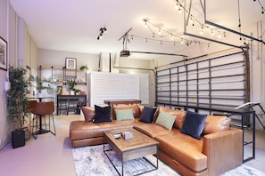A modern living room with a sectional sofa, a coffee table, and a dining area with chairs. - The Oasis Retreat +Pool +Game Room +Basketball + Massive Yard +Near Beach & Golf (Largo)