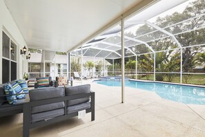 A covered outdoor area with a pool, lounge chairs, and a bench. - The Oasis Retreat +Pool +Game Room +Basketball + Massive Yard +Near Beach & Golf (Largo)