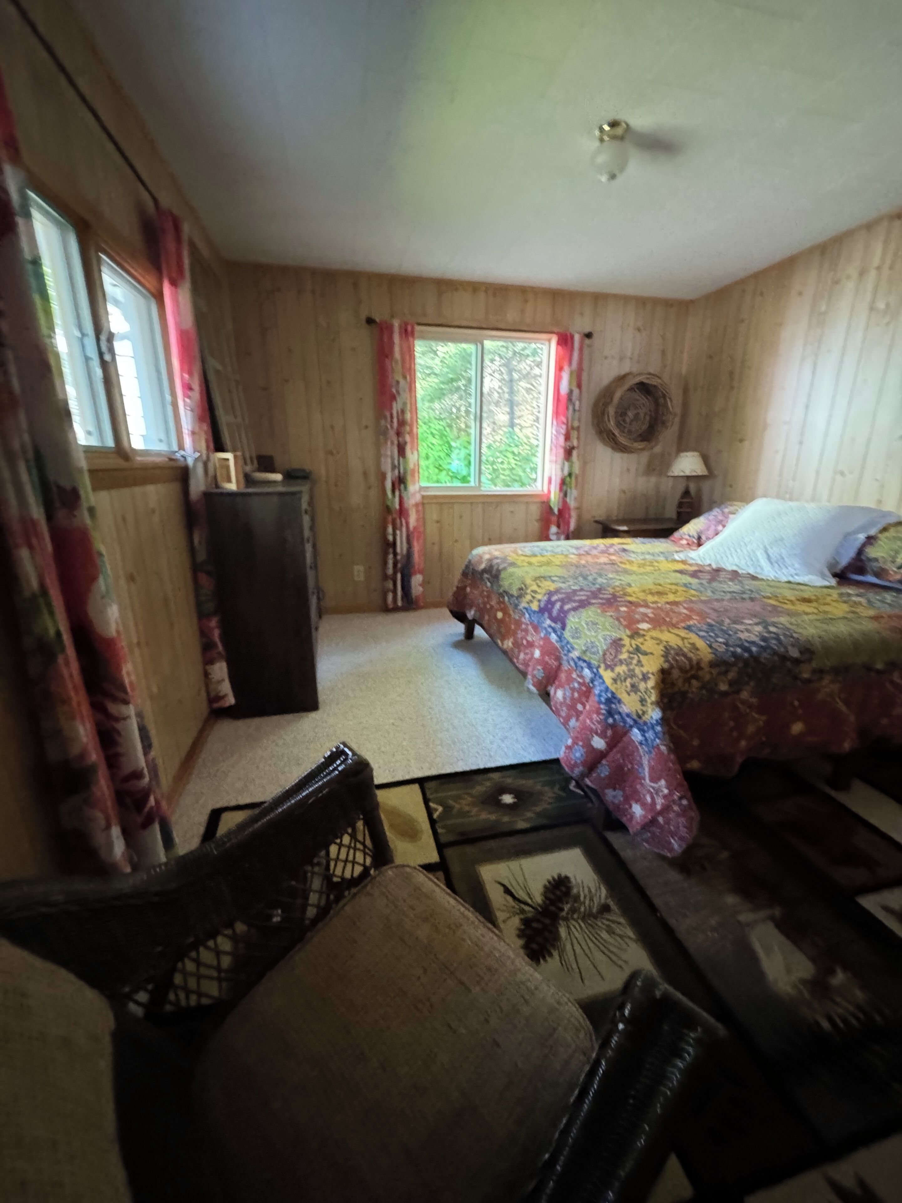 Een gezellige slaapkamer met een bed, een bureau, een stoel en een raam met gordijnen.