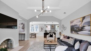 A spacious living area with a fireplace, a sofa, a coffee table, and a dining area in the background. - San Marco Chic Home 2 blocks from San Marco Square (Jacksonville)