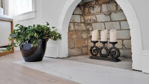 A fireplace with a brick wall, a potted plant, and three candles on a black candle holder. - San Marco Chic Home 2 blocks from San Marco Square (Jacksonville)