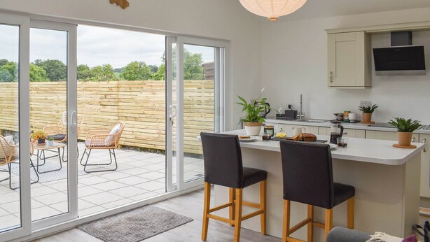 A modern kitchen with a large island, sliding glass doors to a patio, and a skylight. - 2 bedroom accommodation in Abererch (Abererch)