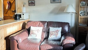 A brown leather sofa with two white cushions, a wooden cabinet, a coffee maker, and a lamp. - 1 bedroom accommodation in Gillamoor, near Kikbymoorside (Gillamoor, near Kikbymoorside)