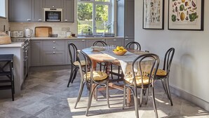 Una cocina moderna con armarios grises, una mesa de comedor de madera y un ventanal grande.