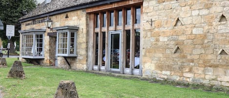 A stone building with large windows and a sign indicating a restaurant.
